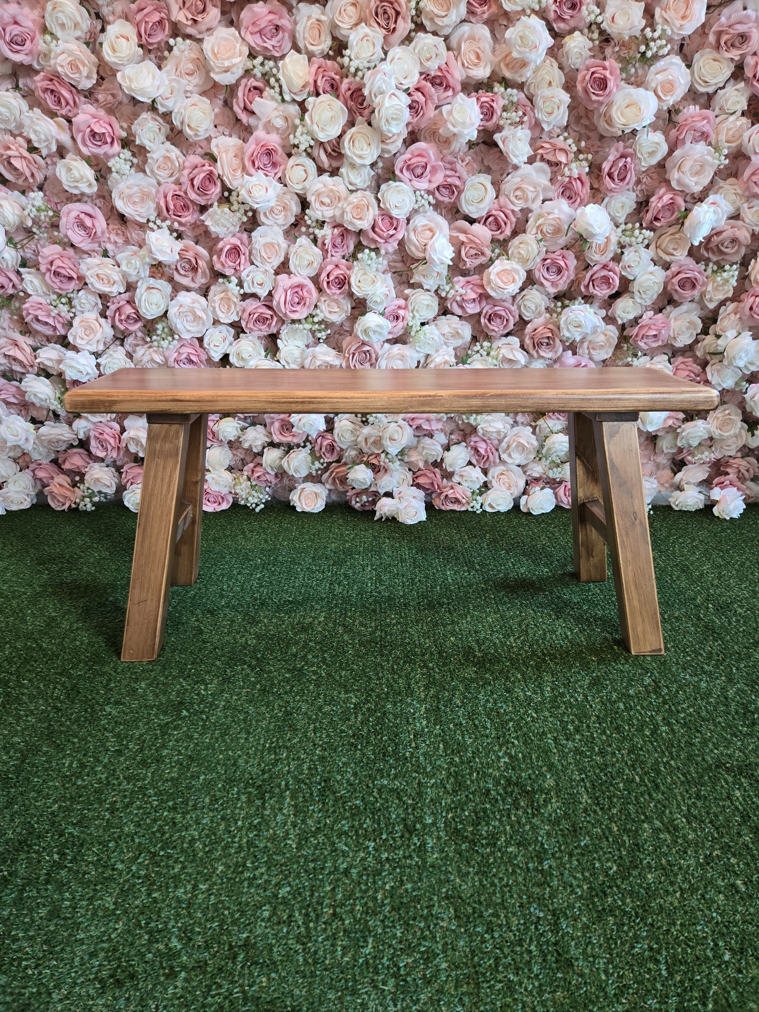 Wood bench in front of a blush flower wall